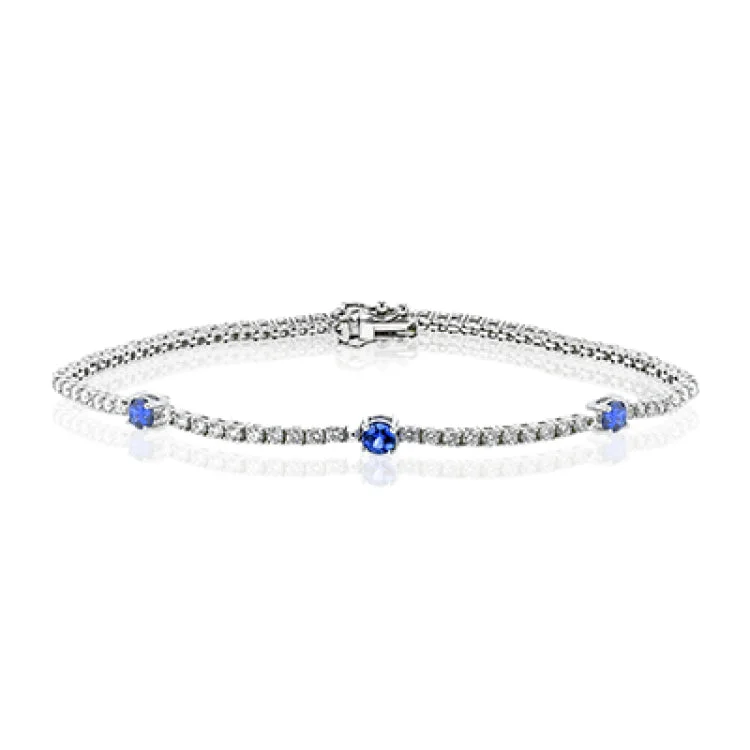 Women’s gold bangle bracelets-This eminently wearable 18k white gold bracelet features three blue sapphire accents that total .60 ctw.